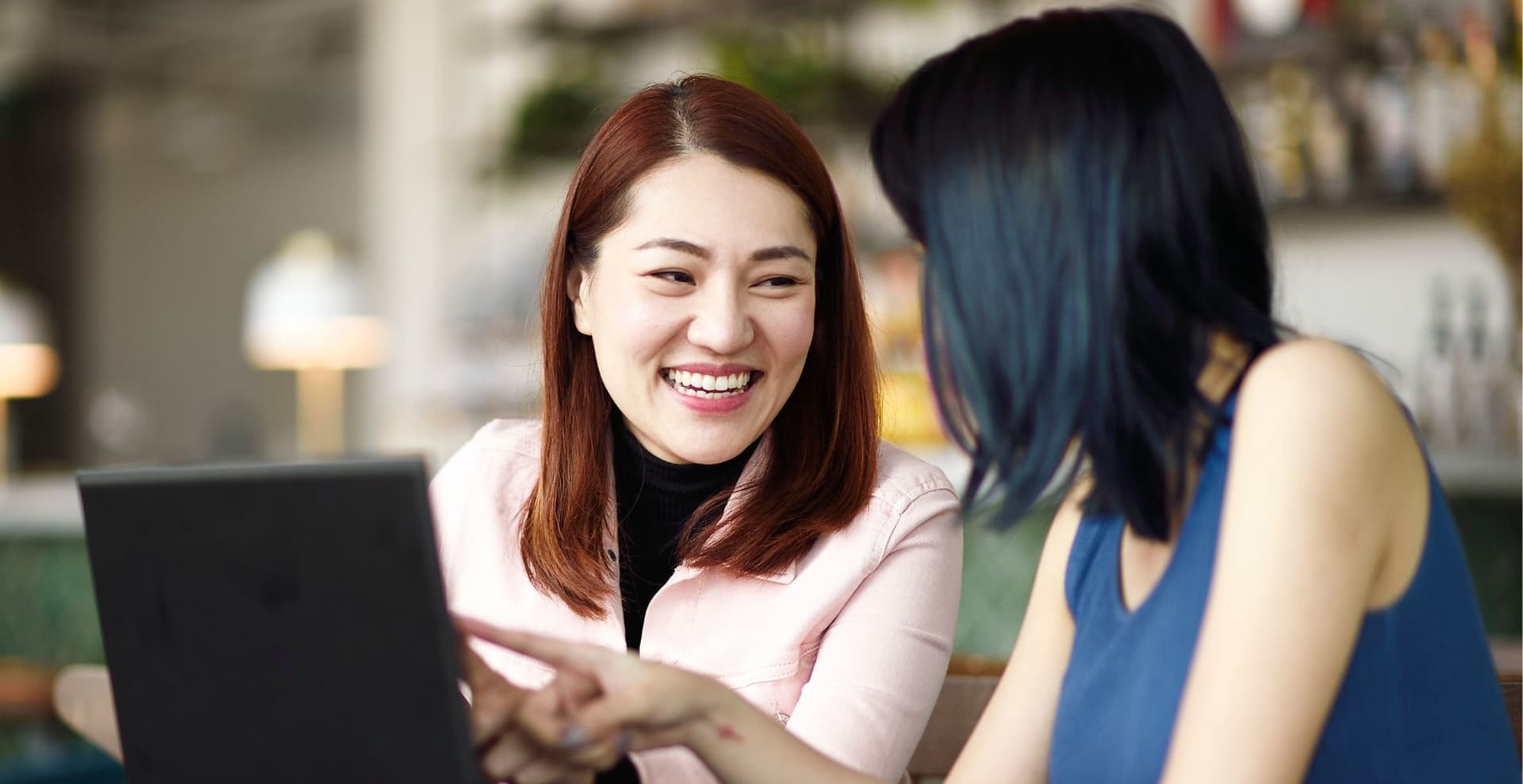 two women talking over laptop